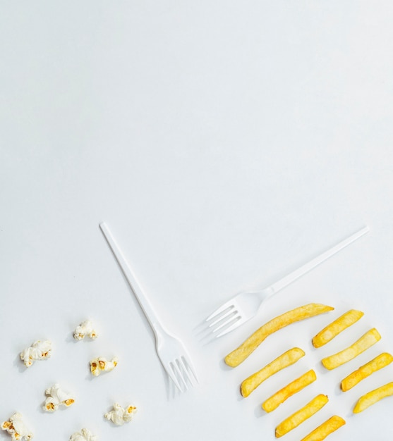 Flat lay of fries with popcorn and forks