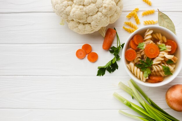 Flat lay fusilli broccoli and carrots in bowl with cauliflower and copy space