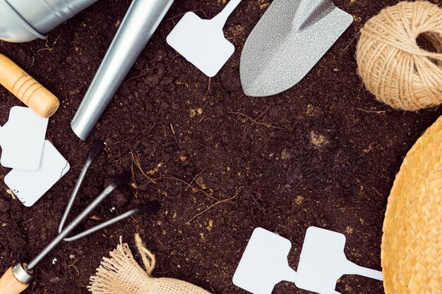Flat lay gardening tools frame on soil with copy space