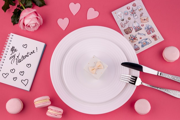 Flat lay of gift box on plate with rose and macarons