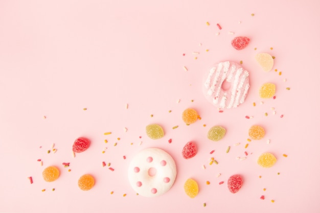 Free photo flat lay of glazed doughnuts with candy and copy space