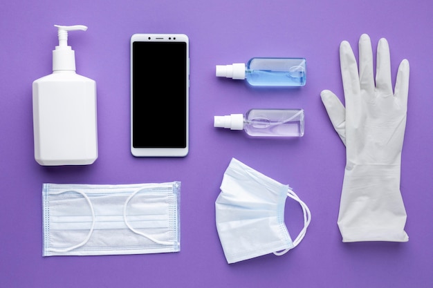 Free photo flat lay of glove with smartphone and medical masks