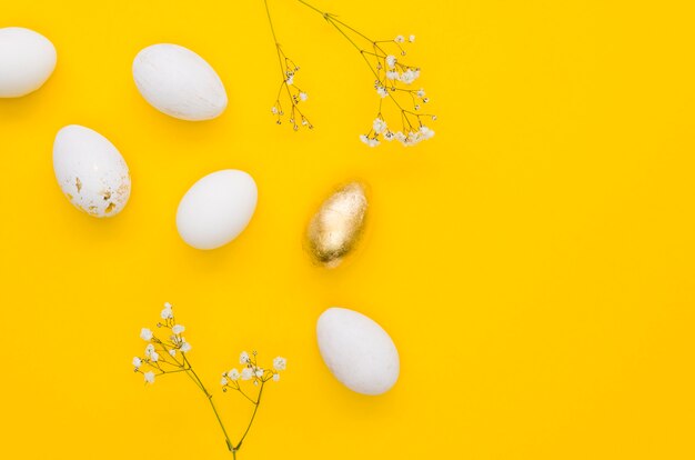 Flat lay of golden easter egg with gyposophila flower