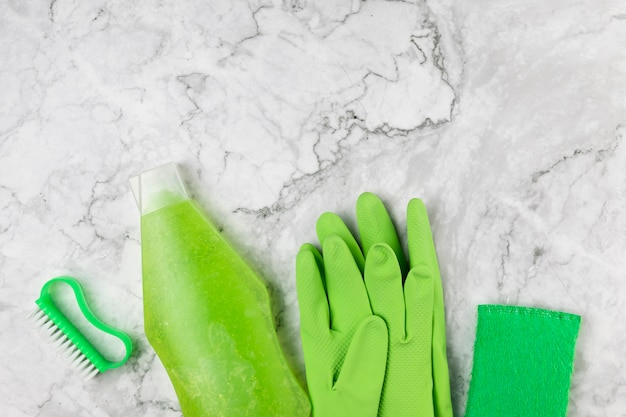 Flat lay green cleaning products on marble background