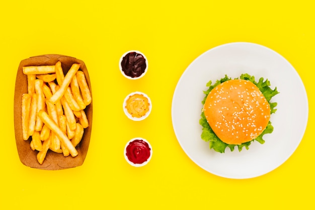 Бесплатное фото Плоский гамбургер с картофелем фри и соусами