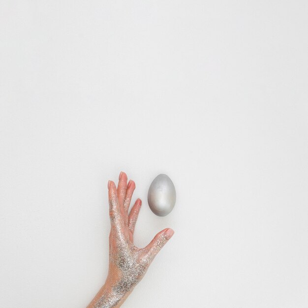 페인트 부활절 달걀으로 반짝이로 덮여 손의 평평하다