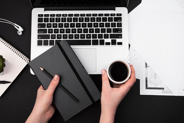 Flat lay of hand holding coffee and agenda