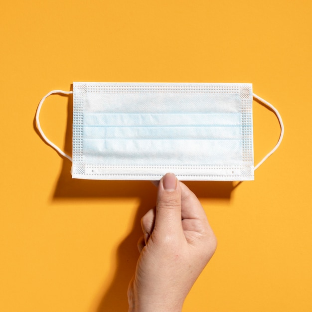 Flat lay of hand holding medical mask