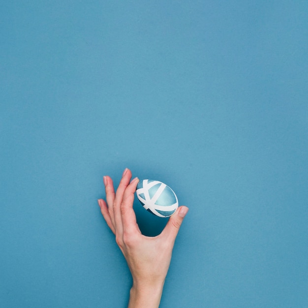 Flat lay of hand holding painted egg for easter with copy space