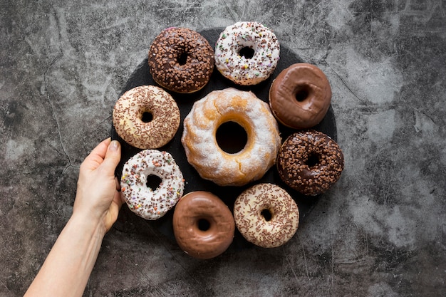 Flat lay of hand holding plate of doughnuts