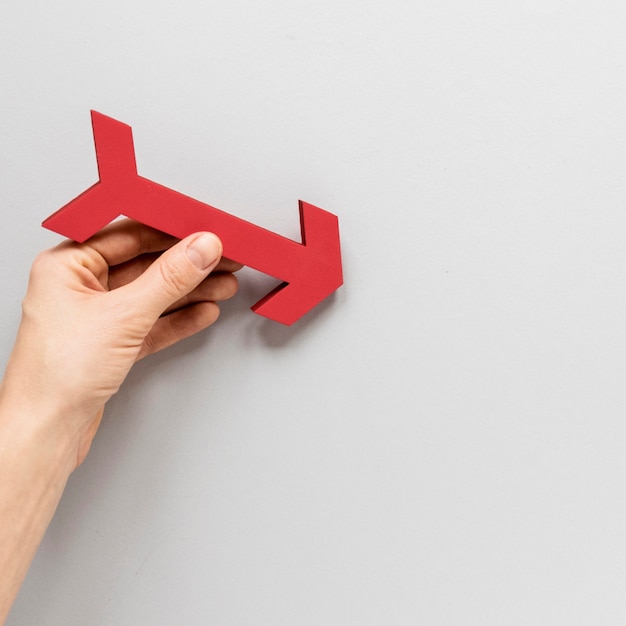 Flat lay hand holding red arrow over white background