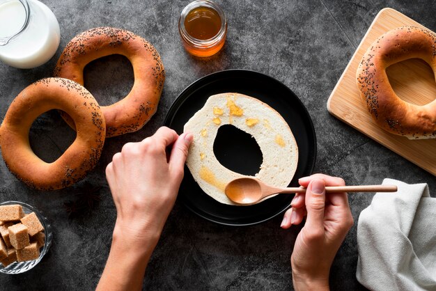 Flat lay hand spreading honey on sliced bagel