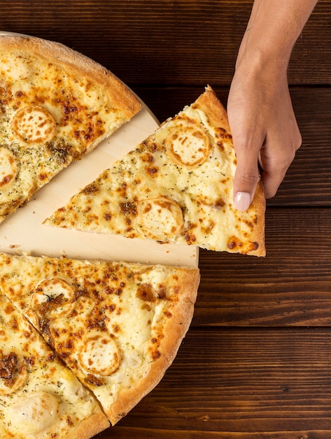 Flat lay hand taking slice of pizza with cheese