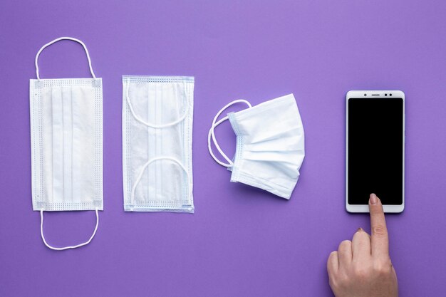 Flat lay of hand using smartphone with medical masks