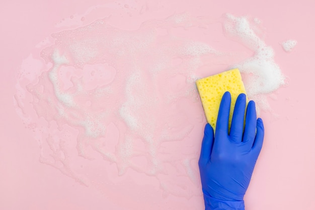 Flat lay of hand with surgical glove cleaning surface with sponge