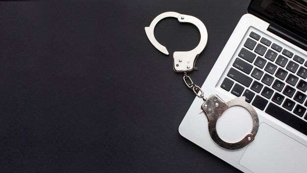 Flat lay of handcuffs with laptop and copy space