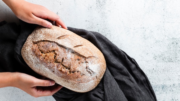 Flat lay of hands holding bread on cloth