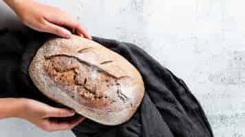 Foto gratuita disposizione piana delle mani che tengono pane sul panno