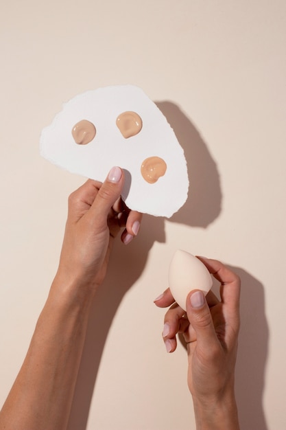 Free photo flat lay hands holding foundation