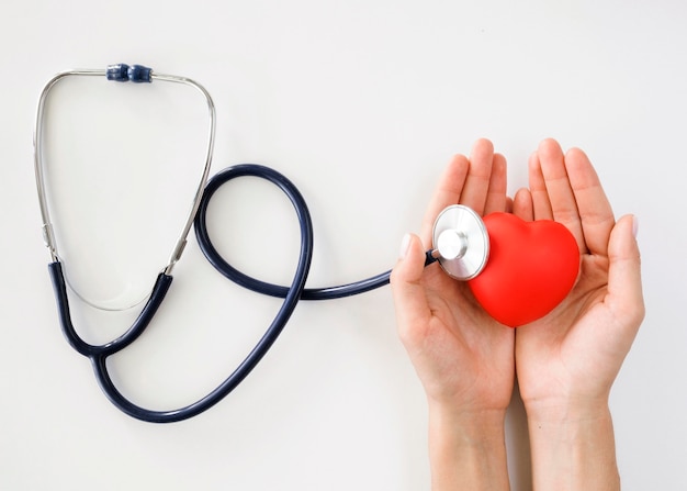 Flat lay of hands holding heart shape with stethoscope