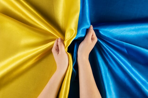 Free photo flat lay hands holding ukrainian flag