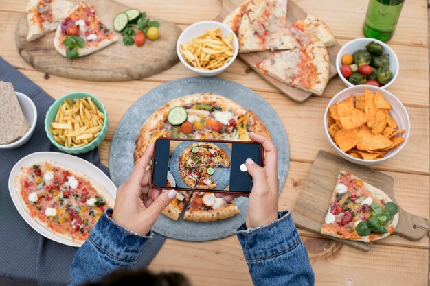 Flat lay hands taking photos with pizza