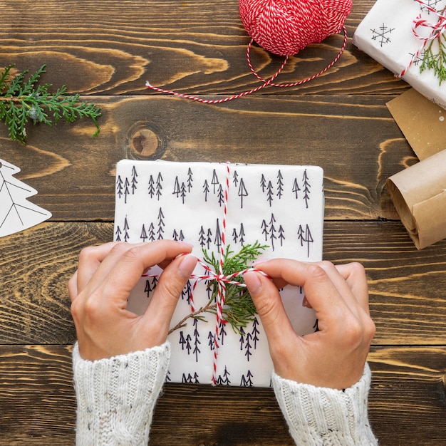 Flat lay of hands tieing christmas gift with string