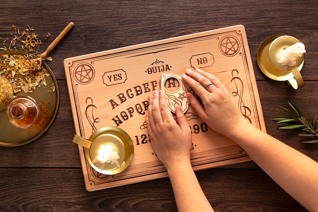 Free photo flat lay hands using ouija board tool