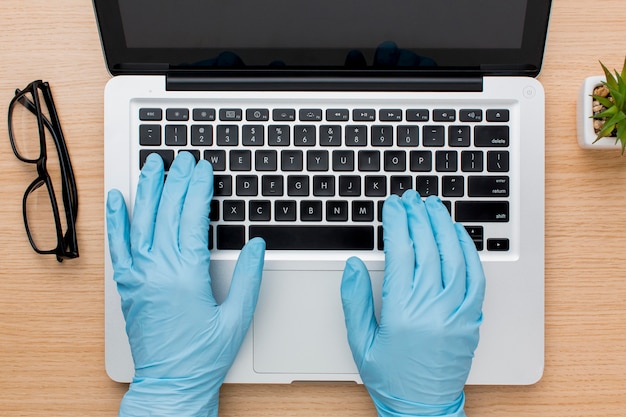 Free photo flat lay of hands with gloves working on computer