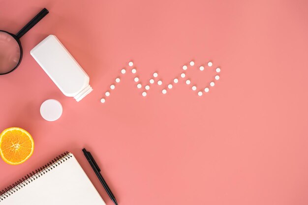 Flat lay heart cardiogram pills on pink background conceptual minimalism