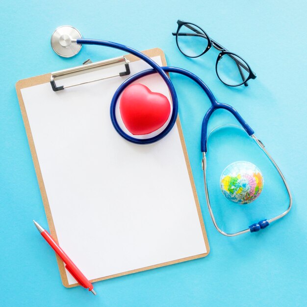 Flat lay of heart shape with stethoscope and notepad