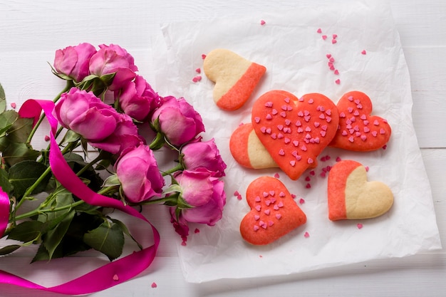 Flat lay of heart-shaped cookie with rose bouquet