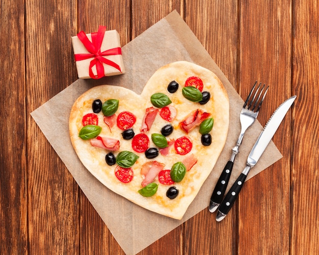 Free photo flat lay heart shaped pizza with tableware