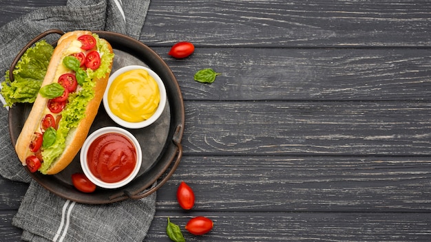 Foto gratuita hot dog piatto con ciotole di salsa