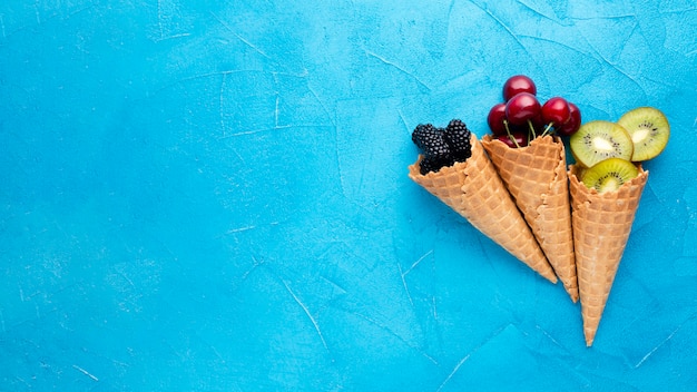 Flat-lay ice cream cones with berries with copy space