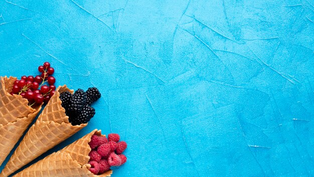 Flat-lay ice cream cones with berries with copy space