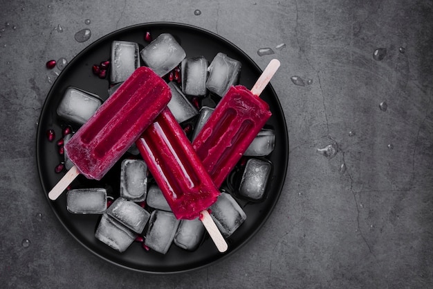 Flat lay ice cream on stick on plate with ice cubes