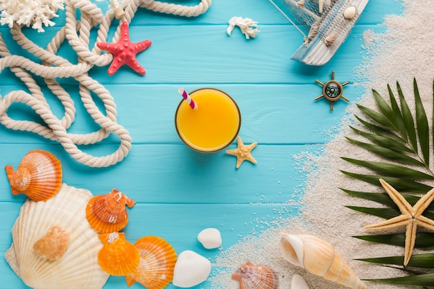 Flat lay juice glass surrounded by beach elements
