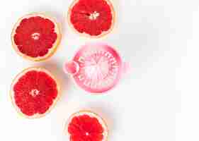 Free photo flat lay juicer and grapefruit in halves