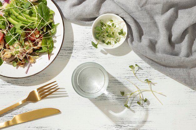 Flat lay of keto diet food containing a salad with chicken and sprouts