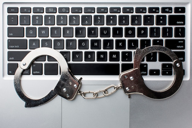 Free photo flat lay of laptop with handcuffs