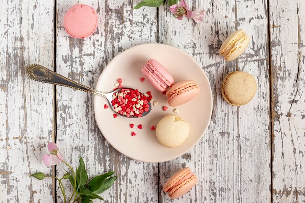 Flat lay of macarons on plate with spoon and flowers