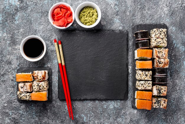 Flat lay maki sushi rolls chopsticks and soy sauce with blank slate