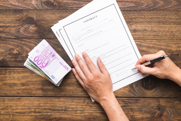 Flat lay man signing a contract on wooden table