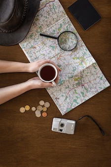 평평한 지도 돋보기 문서와 한 여성의 손에 있는 커피 한 잔