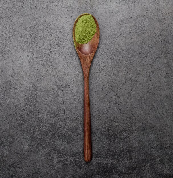 Flat lay of matcha tea powder in wooden spoon