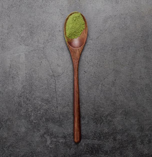 Flat lay of matcha tea powder in wooden spoon