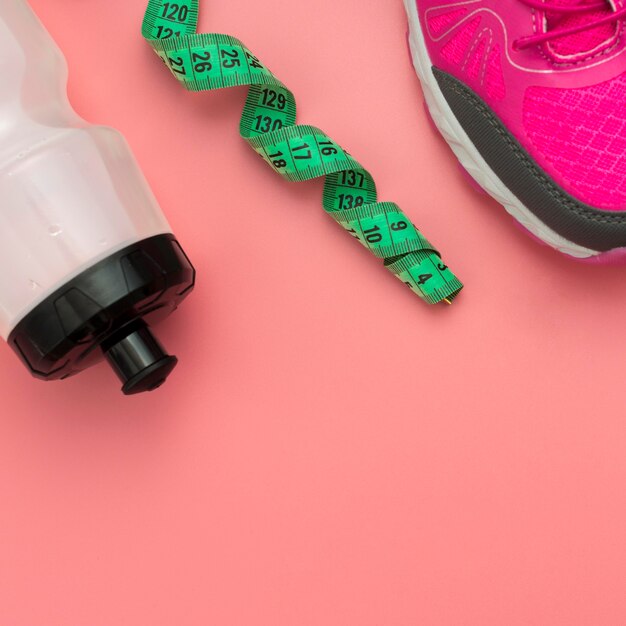 Flat lay of measuring tape with water bottle and sneakers