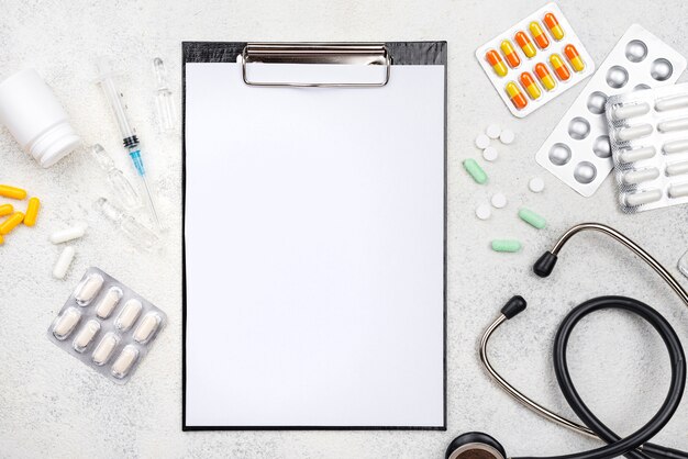 Flat lay medical desk assortment with empty clipboard