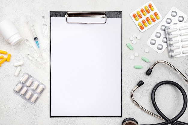 Flat lay medical desk assortment with empty clipboard